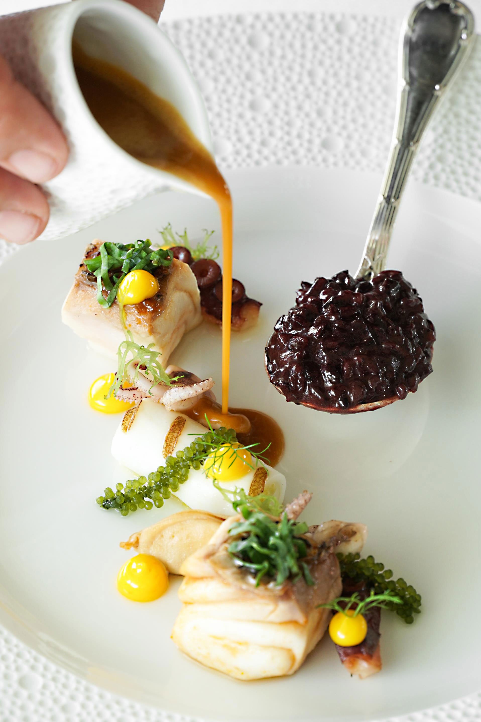 Sauce being poured over a plate of food.